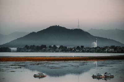 During the day in the mountains there is a white ship near the water
